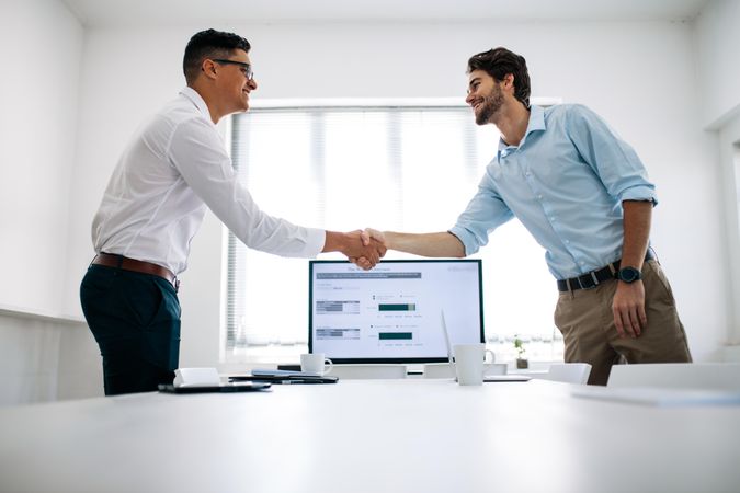 Two businessmen shaking hands at a conference table