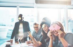 Multi-ethnic group of people smiling while joking around with sticky notes