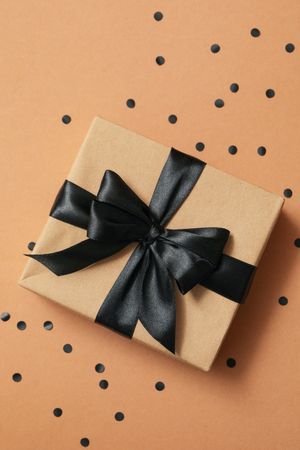 Gift box with dark bow on craft background