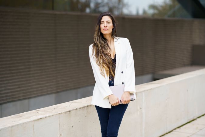 A fashionable and stylish businesswoman is confidently posing outdoors in her chic blazer