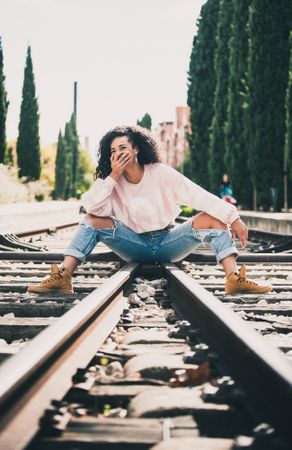 Laughing stylish woman sitting on railway
