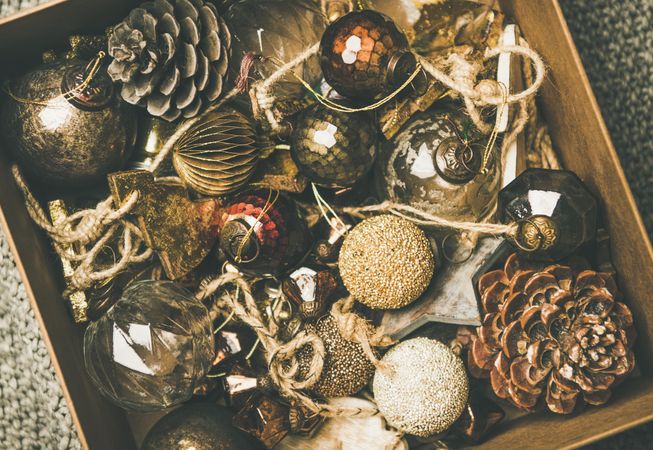 Wooden box full of rustic holiday tree decorations, pine cones, balls and baubles