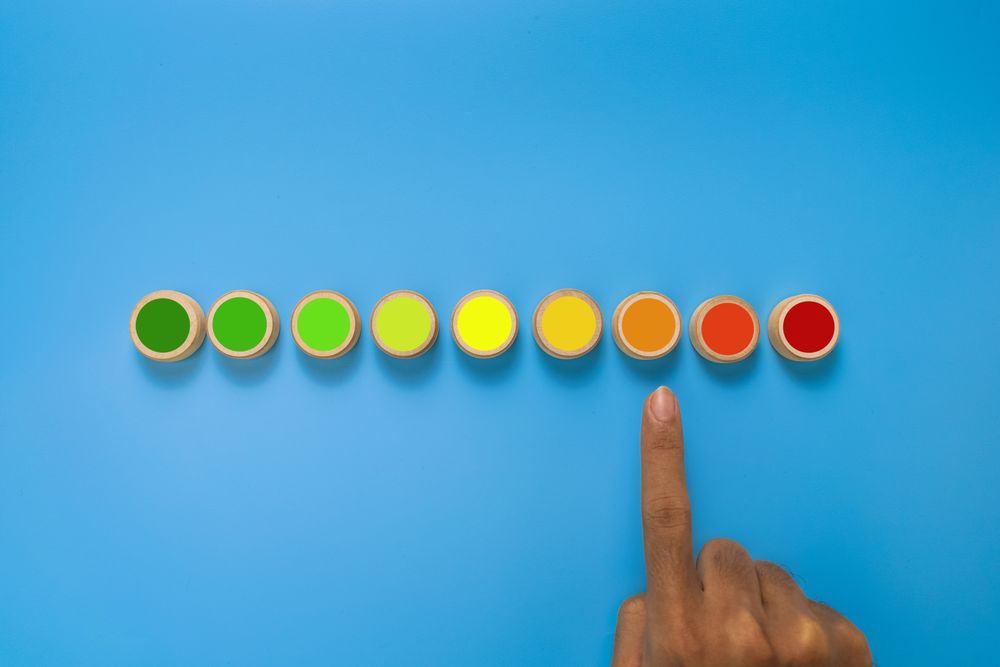 male hand point risk level meter indicator from low to high on wooden blocks. isolated on blue background. concept of risk management