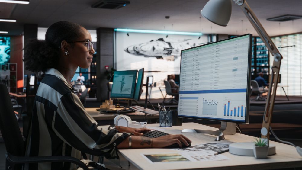 Female Manager Using Desktop Computer With Analytics Software wth Financial Reports.
