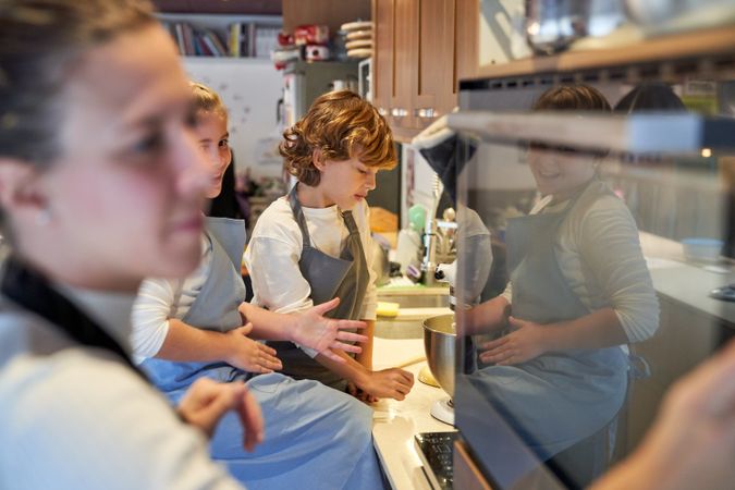 Boy looking at a blender while a girl controls the oven beside her