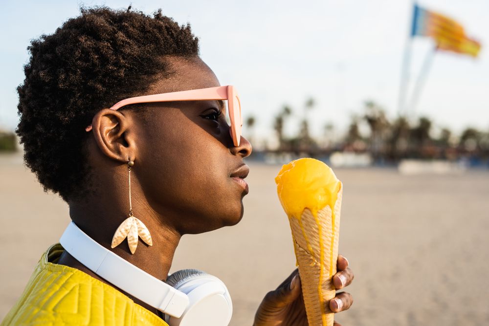 Cool female eating ice cream on beach