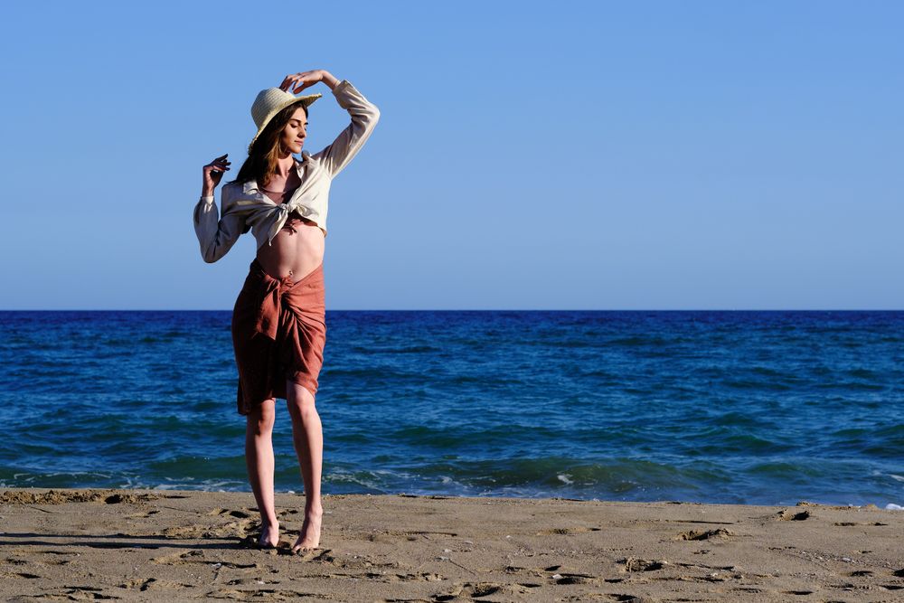 A fashion model with a hat at the beach before sunset