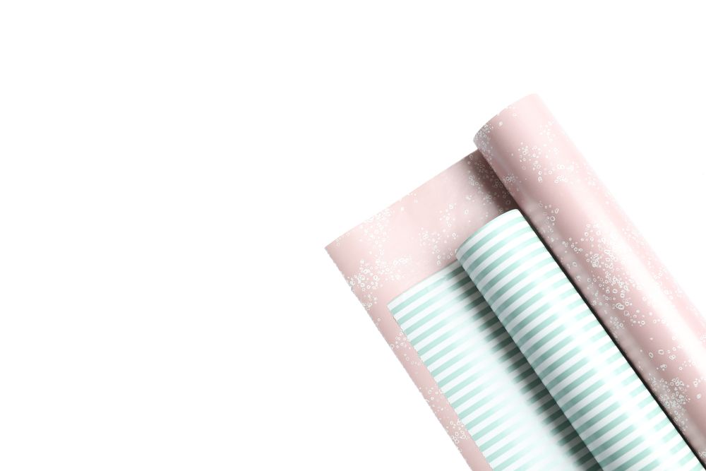 Rolls of festive wrapping paper on plain background. Space for text