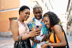 Three friends using smartphone in the street