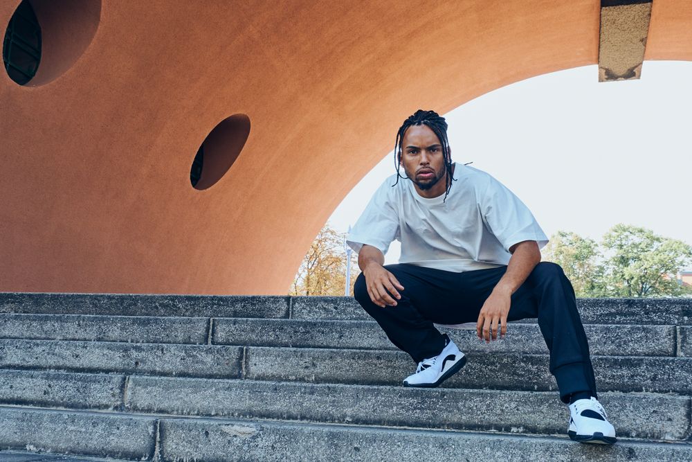 Trendy Black man posing near modern arch