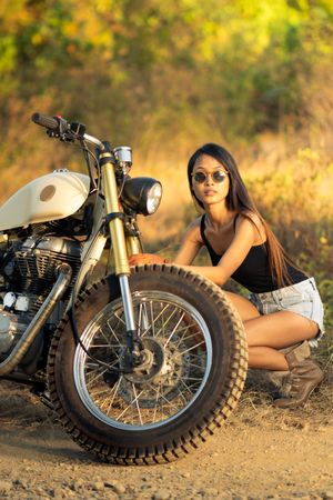 Woman fixing motorbike in countryside