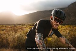 Fit man with tattoos on bicycle ride through the mountains 481O7b