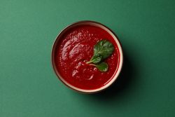 Looking down at bowl of tomato soup on green table