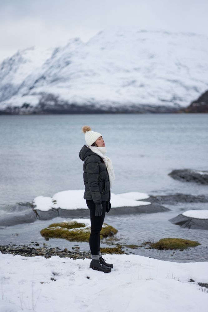 Young asian woman on pond shore against highland in winter