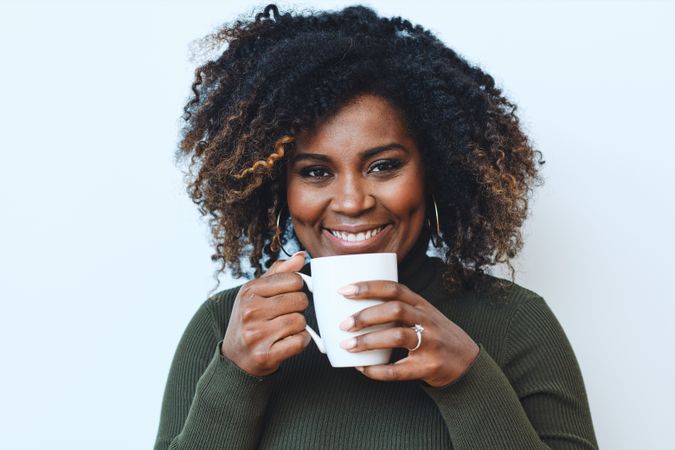 Happy Black woman with cup of coffee