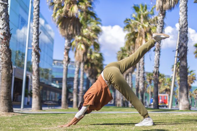 Black female doing downward facing dog under the palms in a promenade