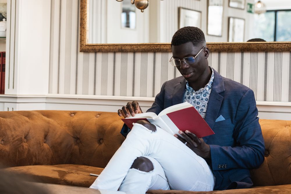 Pensive Black businessman reading book in cafe
