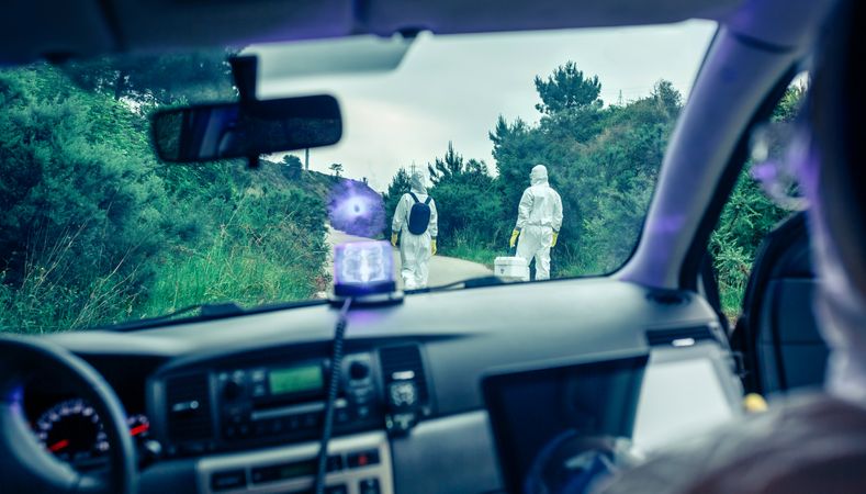 View from inside the car of people in bacteriological protection suits doing research