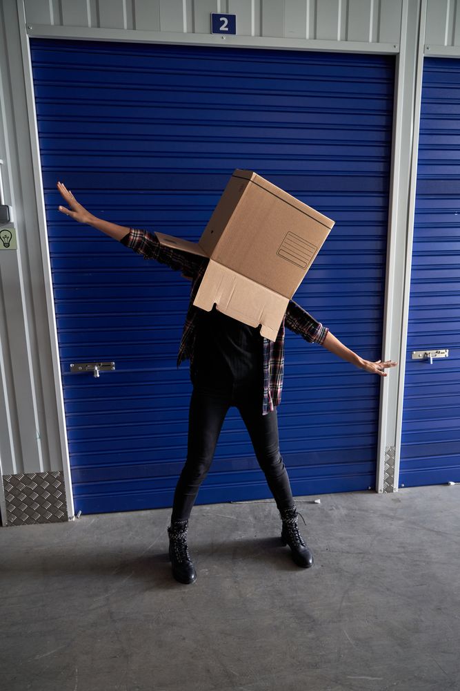 Faceless carefree person with box on head
