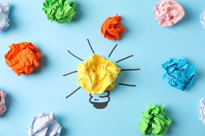 Light bulb and paper balls on blue background, top view