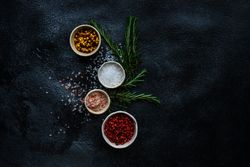 Top view of salt and seasoning bowls and rosemary on kitchen counter with copy space
