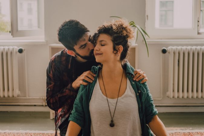 Man rubbing shoulders of joyful woman resting on floor at home