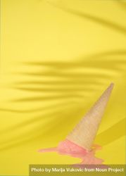 Upside-down cone with pink scoop of melting ice cream on yellow background 0Vl9X4