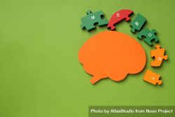 Paper cut out of brain with puzzle pieces on green background, copy space 43Wer4