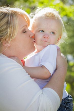 Young Mother Kissing and Holding Her Adorable Baby Boy