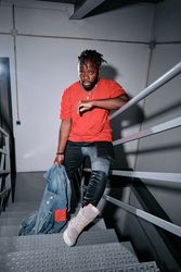 Stylish Black man standing on stairs and leaning on railing