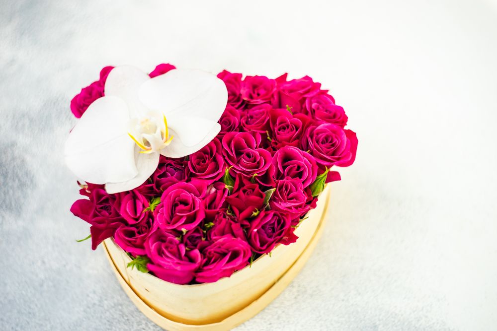 St. Valentine Day heart shaped box full of red roses on stone background with copy space