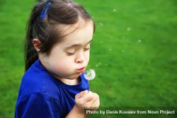 Child blowing dandelion outdoors in a park 49Vxab
