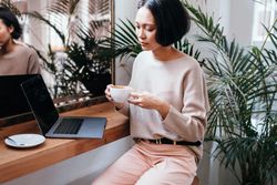 Young woman at a coffee shop with laptop and a drink in hand