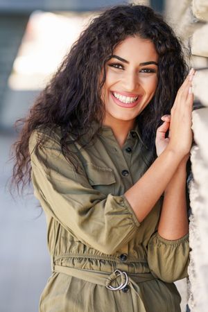 Middle Eastern woman happy while resting on outside wall