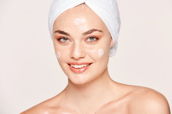 Delighted female with radiant skin applying cream