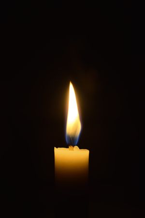 Side view of candle burning in the dark with space for text