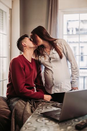 Couple expecting baby kissing at home
