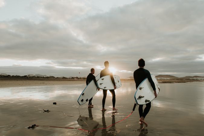 People with surfboard walking near sea