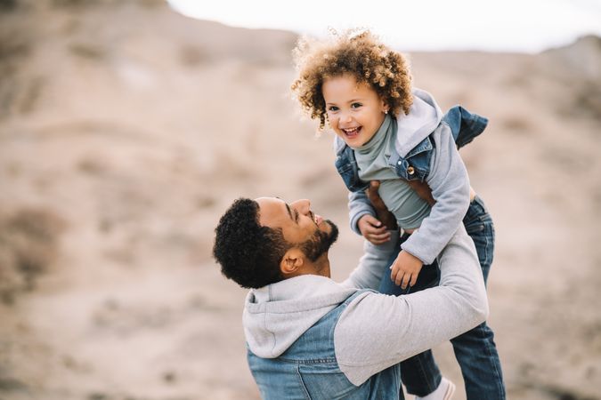 Black father playing with child on ground