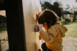Girl holding onto handles on wall at a park outside