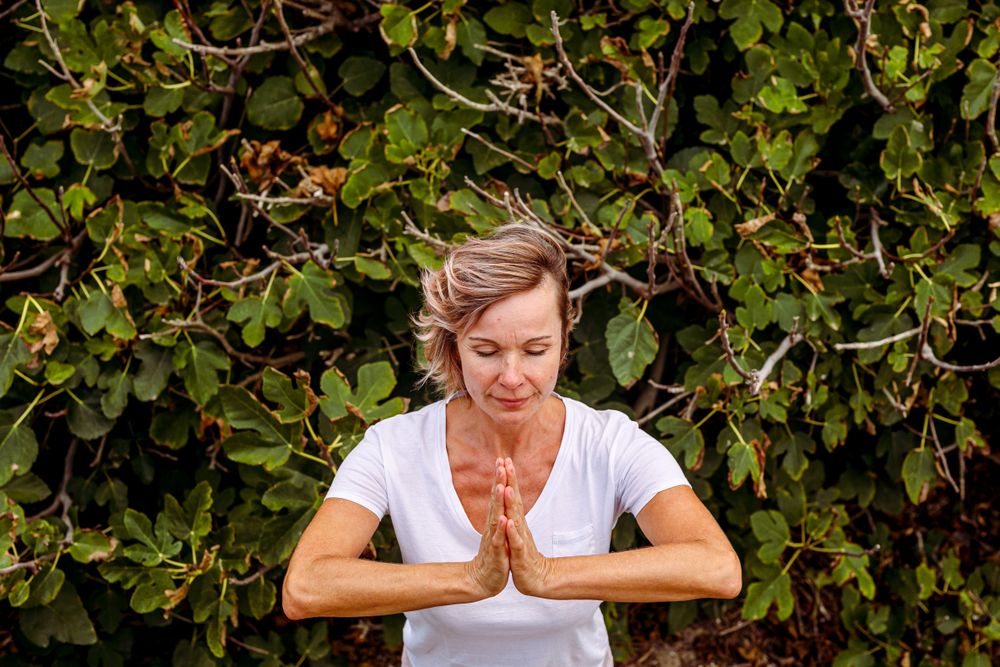 Adult woman meditating near bush