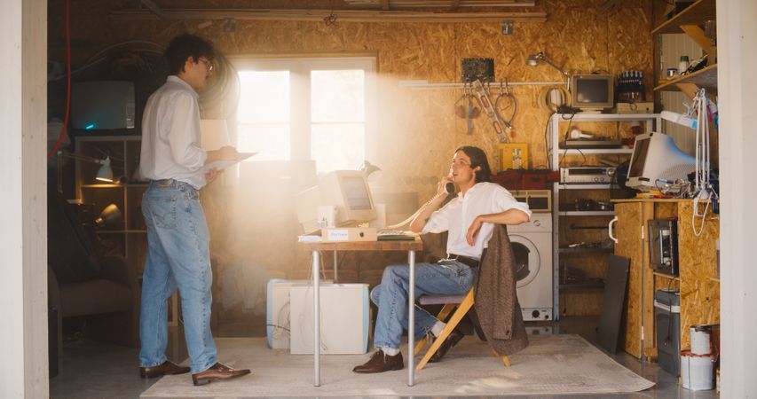 Stock Traders Working In Retro Garage, Using Old Desktop Computer With Candlestick Chart And Landline Phone To Pitch A Public Company To Investors.