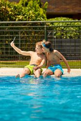 Boys on poolside taking selfie