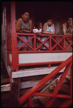 Puerto Rican people leaning on red front porch