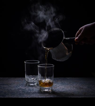 Person pouring hot drink in glass