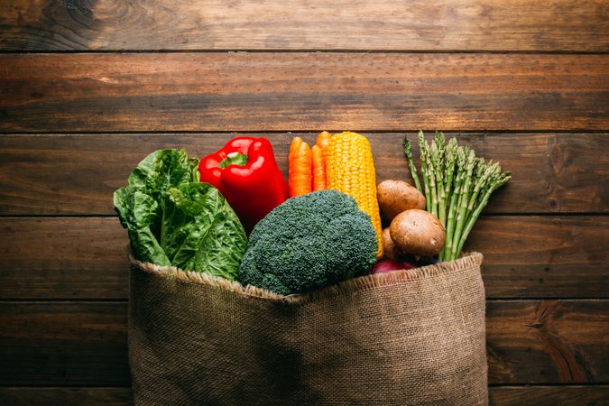 Linen sack with assorted vegetables on table