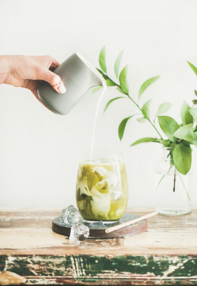 Iced matcha drink with hand pouring cream