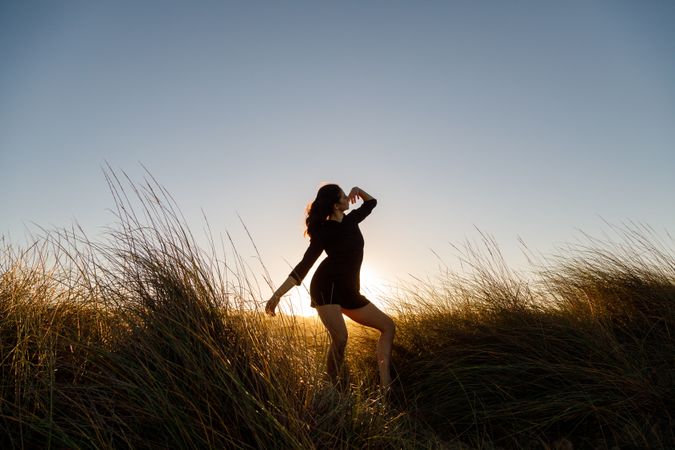 Woman posing between field at sunset