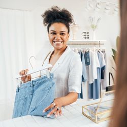 Happy woman about to buy a pair of jeans in a bright shop