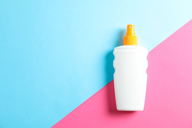 Sunscreen spray on two tone background, space for text